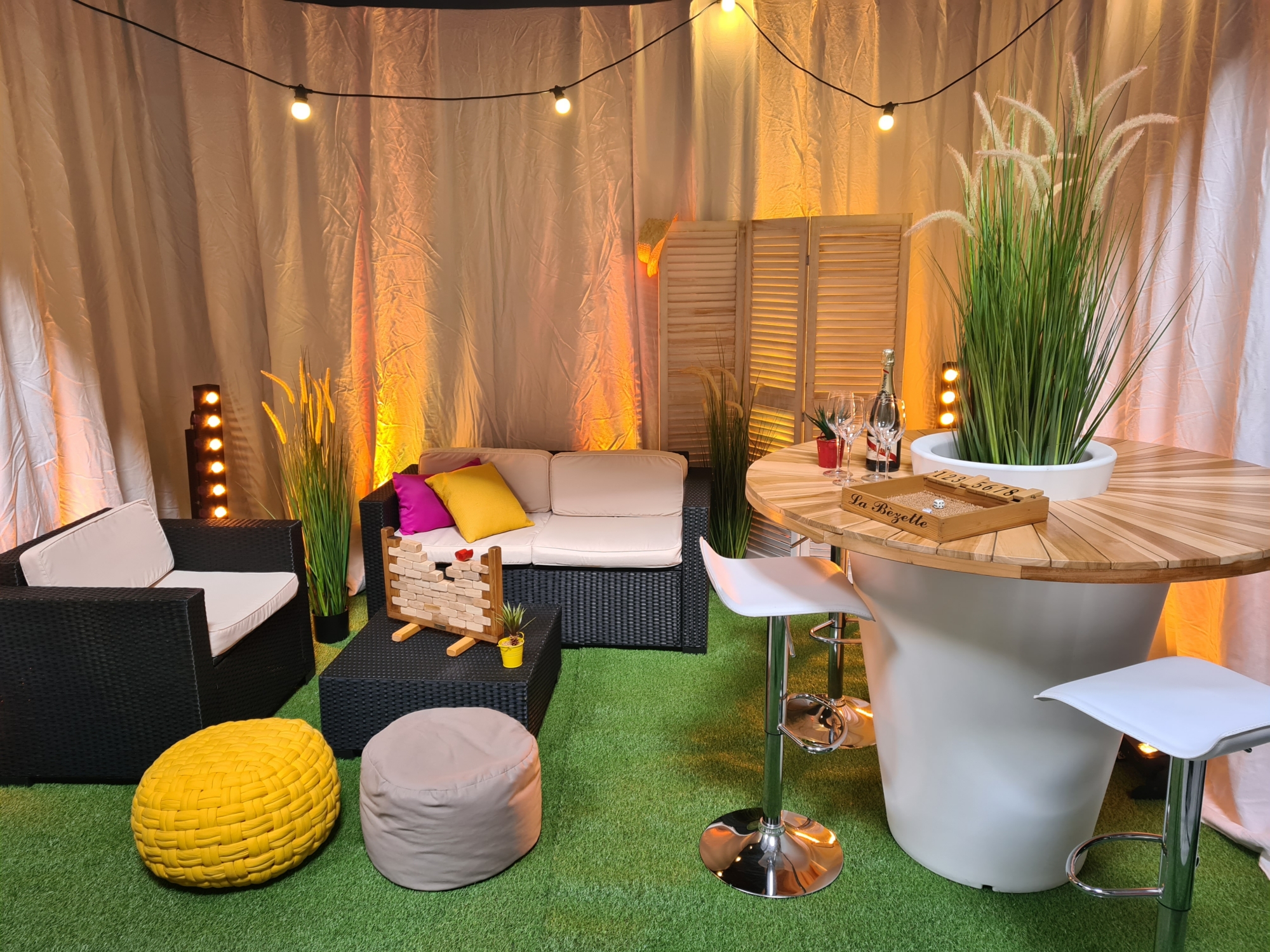 Décor d'ambiance garden party : mobilier lounge, végétation et guirlandes