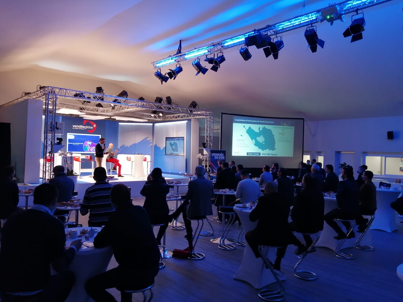 Plénière d'entreprise avec scène, écran de projection et éclairage scénique