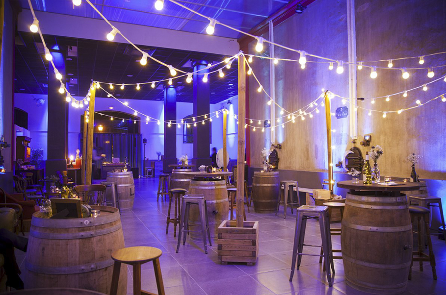 Terrasse en ambiance guinguette avec guirlandes lumineuses et tonneaux